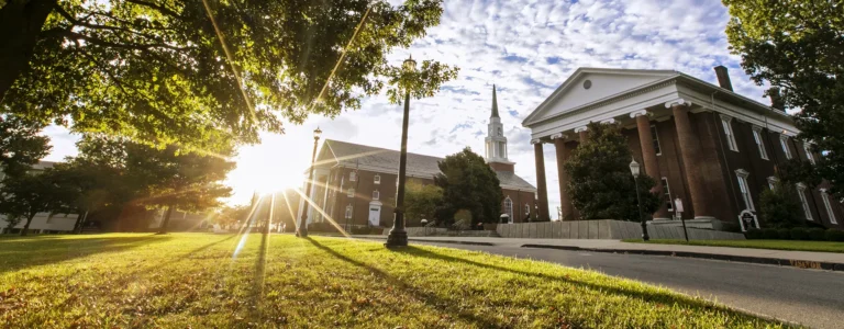 Giddings Hall and John L. Hill chapter with the sun rising over the horizon.